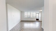 Located at 3967 Lawrence Avenue East in Toronto's Scarborough neighbourhood, this well-appointed one-bedroom, one-bathroom unit offers a thoughtfully designed layout across a single floor. The spacious living room is a standout feature, characterized by large floor-to-ceiling windows that flood the space with natural light and provide open views of the surrounding neighbourhood. Classic parquet hardwood flooring runs throughout the living and bedroom areas, adding warmth and texture to the bright, white-walled interior. A baseboard heating system lines the perimeter of the living room, ensuring year-round comfort. The renovated kitchen is both functional and stylish, featuring white shaker cabinetry, dark countertops, a subway tile backsplash, and a full suite of stainless steel appliances including a refrigerator, dishwasher, microwave, and stove. Light tile flooring completes the clean, modern aesthetic. The generously sized bedroom includes dual sliding mirrored closets offering ample storage, along with a window that brings in natural light. The bathroom is finished with classic white subway tile surrounding a full soaker tub and shower, complemented by a white vanity and neutral tile flooring. A dedicated hallway entry provides a practical transition into the living space.
