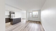 Located on the 8th floor at 90 Duke Street in Hamilton, Ontario, this well-appointed 2-bedroom, 2-bathroom unit offers a thoughtfully designed layout across a single floor. The open-concept kitchen and living area serves as the heart of the unit, showcasing a modern kitchen with two-tone cabinetry — white upper cabinets paired with dark wood-grain lower cabinets — a clean white quartz island, and a full suite of stainless steel appliances including a refrigerator, stove, and built-in microwave. Recessed lighting illuminates the space, complementing the light hardwood-style flooring that runs consistently throughout. The spacious primary bedroom features a window with outdoor views of the surrounding Hamilton cityscape and greenery, filling the room with natural light. The second bedroom includes a sliding closet and similarly benefits from the unit's clean, bright aesthetic. Both bathrooms are finished with modern fixtures; one features a dark wood-grain vanity with a medicine cabinet mirror, while the other includes a soaker tub with full-height taupe tile surround. Clean white walls and minimalist finishes give the entire unit a fresh, contemporary feel, making it a functional and stylish space.