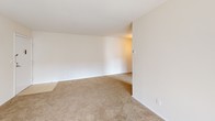 This single-floor residence offers a clean, functional layout designed for comfortable everyday living. The spacious living area is finished with plush wall-to-wall carpeting and neutral tones throughout, creating a bright and welcoming atmosphere. A sliding glass door floods the living space with natural light and provides convenient outdoor access. The kitchen is well-equipped with warm-toned wood cabinetry extending from floor to ceiling, dark countertops, a stainless steel electric range, built-in dishwasher, and a stainless steel sink — all finished with tile flooring for easy maintenance. The bedroom areas are generously sized, each featuring soft carpeting, large windows with blinds for natural light and privacy, and clean white walls. The primary bedroom includes a walk-in closet, offering ample storage. The full bathroom features a rich wood vanity with a white countertop, a large mirror with overhead lighting, tile flooring, and a tub and shower combination. Throughout the residence, a consistent neutral color palette and clean finishes create a cohesive and move-in ready environment.