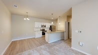 Located at 2605 Sidbury Crossing Dr in Castle Hayne, NC, this well-appointed single-story residence offers a thoughtfully designed layout ideal for comfortable everyday living. The open-concept kitchen and living area serves as the heart of the home, featuring white shaker-style cabinetry, granite countertops, a subway tile backsplash, stainless steel appliances, and a peninsula island with pendant lighting overhead. Light wood-look flooring runs throughout the kitchen and transitions seamlessly into the carpeted living area. The living room benefits from natural light and French doors that open to an outdoor area, complemented by a ceiling fan above. The bedroom is a comfortable, carpeted retreat with its own ceiling fan, a window with natural views, and direct access to a spacious walk-in closet outfitted with wire shelving systems for generous storage. The bathroom features tile flooring, a white vanity with mirror, and clean, neutral finishes. A dedicated laundry room with tile flooring, wire shelving, and washer/dryer hookups adds everyday convenience. Warm neutral wall tones and consistent finishes throughout lend the space a cohesive and inviting ambiance.