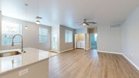 This thoughtfully designed single-story residence offers a comfortable and modern living experience across a well-utilized floor plan. The open-concept kitchen and living area serves as the heart of the home, featuring light-toned luxury vinyl plank flooring, neutral gray walls, and abundant natural light from multiple windows fitted with blinds. The kitchen is a standout space, equipped with gray shaker-style cabinetry, stainless steel appliances including a refrigerator, range, and microwave, and a generous center island topped with light granite countertops. Pendant lighting and recessed ceiling lights add a refined touch to the kitchen area. A ceiling fan enhances comfort in the living area, which also features convenient in-unit washer and dryer connections. The bedroom offers a comfortable retreat with plush carpet flooring, a large window allowing natural light, and ample space for furnishings. The bathroom is finished with a gray vanity, granite countertop, a large mirror, and a shower-tub combination. A dedicated closet and hallway complete the layout. Clean lines, consistent finishes, and a neutral color palette give this residence a fresh, move-in-ready appeal.