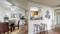 Located at 401 W Orangewood Ave in Anaheim, CA, this single-story, one-bedroom, two-bathroom residence offers a well-designed layout that maximizes functionality and comfort. Wood-look flooring flows throughout the main living areas, complemented by textured ceilings and a warm, neutral color palette.

The kitchen features warm-toned cabinetry, granite-look countertops, and full appliances including a range, microwave, refrigerator, and dishwasher. A pass-through bar with seating connects the kitchen to the dining area and living spaces, fostering an open, social atmosphere. The adjacent dining area accommodates a full dining set and is brightened by a ceiling fan and wall mirror that enhance the sense of space.

The living room is generously proportioned, filled with natural light from sliding glass doors that open to a private patio — ideal for indoor-outdoor living. The bedroom is a comfortable retreat featuring soft carpet, a soothing accent wall, and ample closet space. Two full bathrooms serve the home; one includes a soaking tub with elegant green subway tile surround and hardwood-style flooring. The private patio rounds out this well-appointed residence, offering a quiet outdoor extension of the living space.