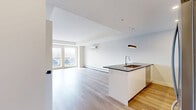 This well-appointed 2-bedroom, 1-bathroom unit at 6450 Bayers Road in Halifax, Nova Scotia offers a thoughtfully designed open-concept layout with clean, modern aesthetics. Light hardwood flooring flows seamlessly throughout the entire space, complementing the bright white walls and creating a warm, cohesive feel.

The open-concept kitchen and living area serves as the heart of the unit. The kitchen features sleek white cabinetry, dark countertops, stainless steel appliances including a refrigerator, stove, and built-in microwave, a wood-toned tile backsplash, and a central island with a sink and pendant lighting above. The living area is spacious and sun-filled, with large windows offering outdoor views and a wall-mounted mini-split unit providing climate control alongside baseboard heating.

Both bedrooms are generously sized with ample natural light from well-positioned windows. The primary bedroom includes a built-in closet with shelving and direct access to the bathroom. A second closet provides additional storage elsewhere in the unit.

The bathroom is clean and modern, featuring a walk-in shower, a dark-countered vanity, and wood-toned flooring. A utility room rounds out the functional layout. Throughout, matte black hardware accents add a contemporary finishing touch.
