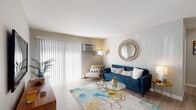 Located at 824 W Panorama Dr in Palatine, IL, this single-floor unit offers a well-organized layout with distinct living, sleeping, kitchen, and bathroom areas. The living room is a standout space, featuring light wood-style flooring, neutral walls, and large sliding glass doors dressed with vertical blinds that invite generous natural light. A wall-mounted air conditioning unit provides climate control, and the open feel of the room comfortably accommodates a full seating arrangement.

The kitchen is equipped with dark espresso-toned cabinetry, granite-look countertops, and stainless steel appliances including a refrigerator and dishwasher. Light wood flooring continues throughout, giving the kitchen a clean, modern appearance with ample counter and storage space along both walls.

The bedrooms are carpeted and feature ceiling fans with integrated lighting. Each room benefits from natural light provided by windows with horizontal blinds, creating a calm and restful atmosphere. The rooms offer enough space for full furniture arrangements.

The bathroom features a dark wood vanity with a white countertop and sink, a framed mirror, and light wood-style flooring, maintaining the cohesive, updated aesthetic found throughout the rest of the unit.