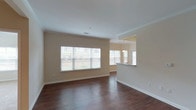 This single-floor residence offers a thoughtfully designed layout across two bedrooms and two full bathrooms. The open living and dining area is defined by rich, dark hardwood-style flooring and crowned with classic crown molding. A standout architectural feature is the decorative columned archway that elegantly separates the living space from a defined dining area, which includes a tray ceiling detail that adds visual depth. Large windows along the living area allow natural light to fill the space, enhancing its open, airy feel.

The kitchen connects to the main living area via a pass-through counter, which is fitted with dark cabinetry and includes a black refrigerator. The bedrooms are carpeted for comfort and each features a ceiling fan with a window for natural light. Both full bathrooms are finished consistently, featuring rich, dark wood cabinetry, light countertops, tile flooring, a vanity with mirror, and a tub/shower combination.

A dedicated in-unit laundry area accommodates a full-size washer and dryer with wire shelving above for additional storage. The residence also includes an attached garage with an automatic opener, providing secure, convenient parking and extra storage potential.