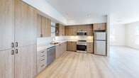 Located in Liberty Lake, WA, this thoughtfully designed 3-bedroom, 2-bathroom unit offers a clean, contemporary aesthetic across a single level of comfortable living space. Light-toned hardwood-style flooring runs throughout, creating a cohesive and bright atmosphere from room to room.

The kitchen is a standout feature, showcasing warm wood-grain cabinetry, light countertops, a stainless steel appliance suite including a gas range, microwave, dishwasher, and refrigerator, and recessed lighting overhead — all contributing to a functional yet stylish cooking environment.

Each of the three bedrooms is finished with the same light flooring and neutral walls, offering a clean canvas. The bedrooms are equipped with individual wall-mounted mini-split climate control units, ensuring personalized comfort. Natural light fills the rooms through sizable windows fitted with horizontal blinds, with views of surrounding greenery. The primary bedroom includes a sliding closet and direct access to one of the two full bathrooms.

Both bathrooms are designed with a consistent modern style, featuring tub-shower combinations with curved chrome curtain rods, wood-toned vanities with light countertops, and durable hardwood-style flooring. Additional spaces include a utility room, a closet, and a connecting hallway that ties the layout together efficiently.