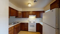 This single-floor residence in Burbank, Illinois, offers a practical and well-organized layout with two bedrooms and one and a half bathrooms. The kitchen is a notable feature, designed in an L-shaped configuration with rich, dark-stained wood cabinetry extending from floor to ceiling. Ample upper and lower cabinet storage is complemented by light-colored countertops, a double-basin sink, a gas range with overhead ventilation, and a full-size refrigerator. The flooring in the kitchen features a durable, neutral-toned vinyl surface, and overhead flush-mount lighting provides consistent illumination.

The two bedrooms are carpeted in a warm, neutral tone and feature clean white walls. One bedroom includes a sliding glass door with vertical blinds, allowing natural light and outdoor access, while the second bedroom features a standard window with horizontal blinds. A ceiling fan with integrated lighting is present in the living area, adding both functionality and airflow.

The full bathroom is equipped with a tub-shower combination, a single-sink vanity with wood cabinetry, and vinyl flooring. The half bathroom includes a vanity with matching wood cabinetry and a toilet. Both bathrooms maintain a clean, functional aesthetic consistent with the rest of the unit.