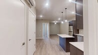 Located at 6200 E 3rd St in Superior, Wisconsin, this single-floor unit offers a well-designed layout that makes efficient use of its space. The open-concept kitchen and living area serves as the heart of the home, featuring rich dark-stained cabinetry, crisp white countertops, and a full suite of stainless steel appliances including a refrigerator, range, microwave, and dishwasher. A center island with pendant lighting above adds both functionality and a modern aesthetic, while recessed lighting illuminates the space throughout. Light wood-style vinyl plank flooring flows seamlessly across the entire unit, creating a cohesive and clean look. Neutral warm-gray walls provide a versatile backdrop throughout. The bedroom is a comfortable, well-proportioned room equipped with a ceiling fan, a wall-mounted mini-split unit for individualized climate control, a baseboard heater, and a window offering natural light and exterior views. A sliding double-door closet provides ample storage. The hallway connecting the bedroom to the main living area includes additional closet space and a thermostat, keeping the layout practical and organized. The overall design is modern and move-in ready, with consistent finishes that give the space a polished, unified character.