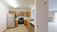 Located at 3280 Hillside Dr in Delafield, Wisconsin, this 2-bedroom, 1-bathroom single-floor residence offers a practical and comfortable layout designed for everyday living. The kitchen features warm honey-toned wood cabinetry, light countertops, and a full suite of stainless steel appliances including a refrigerator, electric range, and dishwasher, all set over easy-to-maintain luxury vinyl plank flooring. The spacious living area is carpeted and filled with natural light through a large sliding glass door that opens to an exterior view, complemented by baseboard heating throughout. The primary bedroom is a well-proportioned retreat with a window that brings in natural light, while the second bedroom features a charming French glass-paned door and its own window with neighborhood views, along with a built-in closet with bi-fold wood doors. The full bathroom is clean and bright, offering a wide vanity with ample counter space, a tub-shower combo, and wood-look flooring. A dedicated in-unit laundry room with full-size washer and dryer and wire shelving above adds exceptional convenience. The unit's neutral palette and consistent finishes create a cohesive, move-in-ready atmosphere throughout.
