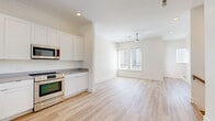 This contemporary 3-floor residence is designed with a clean, modern aesthetic defined by crisp white walls, light hardwood flooring, and an abundance of natural light. The open-concept living and kitchen area on the main level seamlessly connects the two spaces, creating a welcoming and functional layout. The kitchen is well-appointed with white shaker-style cabinetry, neutral gray countertops, stainless steel appliances including a range, microwave, dishwasher, and refrigerator, as well as an undermount sink. A ceiling fan adds comfort to the adjacent living area, which is brightened by large windows with blinds. The bedrooms are generously proportioned, each featuring light hardwood floors, neutral wall tones, and windows that invite natural light and neighborhood views. One bedroom includes an ensuite bathroom and a walk-in closet, offering added privacy and convenience. The bathroom is outfitted with a full tub-shower combination, chrome fixtures, and a teal accent wall that adds a subtle pop of color. Throughout all three floors, the consistent use of light tones and quality finishes creates a cohesive, move-in-ready environment that is both functional and visually appealing.