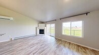 Located at 601 County U in Wrightstown, Wisconsin, this well-appointed one-bedroom, one-bathroom unit offers a thoughtfully designed single-floor layout with modern finishes throughout. Light-toned luxury vinyl plank flooring flows seamlessly across every room, complementing the clean, neutral color palette that gives the space a bright and airy feel.

The open-concept kitchen and living area serves as the heart of the unit. The kitchen is outfitted with rich, dark wood cabinetry, striking granite countertops, stainless steel appliances including a range, microwave, and refrigerator, and a large island with a sink — ideal for both cooking and casual dining. The living room is anchored by a corner fireplace and features sliding glass doors that open to a balcony with open views of the surrounding landscape, filling the space with natural light.

The generously sized primary bedroom includes a ceiling fan, a bright window, and access to a spacious walk-in closet with wrap-around wire shelving. The full bathroom features a dark-toned vanity with a granite countertop, a mirror, and a shower/tub combination. A dedicated laundry area and hallway round out the layout, offering practical convenience. Baseboard heating is present throughout the unit.