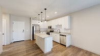 Located at 1335 S Taylor Ave in St. Louis, MO, this single-floor unit offers a thoughtfully designed interior with modern finishes throughout. The kitchen serves as the centerpiece of the space, featuring crisp white cabinetry, granite countertops, and a classic subway tile backsplash. A central island provides additional prep and seating space, illuminated by a trio of matte black pendant lights. Stainless steel appliances, including a refrigerator, range, microwave, and dishwasher, complete the well-equipped kitchen. Wood-look plank flooring runs seamlessly throughout the unit, adding warmth and visual continuity.

The living area benefits from generous natural light provided by large windows fitted with blinds, and a glass-paneled exterior door extends the brightness while offering outdoor access. A ceiling fan in the bedroom enhances comfort, and the bedroom features its own walk-in closet outfitted with wire shelving systems for organized storage.

The bathroom includes a white vanity with a granite countertop, a matte black faucet and fixtures, and a backlit LED mirror that adds a clean, contemporary touch. Neutral tones and recessed lighting throughout contribute to a bright, cohesive ambiance across the entire space.