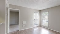 Located in Tampa, FL along North Dale Mabry Highway, this efficiently designed one-bedroom, one-bathroom unit offers a well-organized single-floor layout. The combined living room and kitchen area forms the heart of the space, featuring light wood-look laminate flooring, neutral gray walls, and a textured ceiling throughout. Natural light flows in through a large window and a glass-paneled exterior door fitted with blinds, creating a bright and airy atmosphere. The kitchen is positioned adjacent to the living area in a galley-style layout, complete with white cabinetry, light countertops, a classic white subway tile backsplash, and black appliances including an electric range and dishwasher. A pass-through opening connects the kitchen to the living space, enhancing the open feel. The bedroom is a comfortable, carpeted room featuring a large window with blinds that allows ample natural light, along with a dedicated closet for storage. The bathroom is clean and functional, outfitted with wood-look flooring, a full tub-shower combo with white tile surround, and crisp white fixtures. The layout is practical and cohesive, making efficient use of every square foot throughout the space.