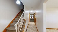Located at 2025 Applegrove St NW in North Canton, Ohio, this multi-level home offers 2 bedrooms, 3 bathrooms, and generous living space spread across three floors plus a full basement. The main level features a bright, open kitchen equipped with stainless steel appliances — including a refrigerator and range — white cabinetry, and durable tile flooring. Natural light filters in through blinds-covered windows, creating a clean and functional cooking space. Two living areas provide flexible use of space; one features a distinctive brick accent wall, vertical wood paneling, and carpeted floors beneath a textured ceiling, lending a classic character to the room. The spacious primary bedroom includes two sets of warm wood-toned closet doors and plush carpet, while the second bedroom also offers dual closets and a window view. The three bathrooms are finished with tile flooring, including one full bath with a tub-shower combination framed by wood-trimmed doors. The unfinished basement provides ample utility and storage space with painted concrete walls, an epoxy-coated floor, and exposed wood-beam ceiling with visible HVAC infrastructure. A staircase connects all levels, and hallways offer smooth transitions throughout the home.