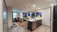 Located at 419 N Herbert Ave in Tucson, AZ, this single-floor residential unit offers a contemporary, energetic living environment with bold design choices and functional layouts. The open-concept kitchen and living area form the heart of the space, where light wood-style flooring flows seamlessly throughout. The kitchen is equipped with stainless steel appliances—including a full-size refrigerator, range, microwave, and dishwasher—complemented by dark wood cabinetry, a tile backsplash, and a spacious island with quartz countertops and pendant lighting overhead. The living area is bright and welcoming, with large windows allowing generous natural light, ceiling fans, and room for comfortable seating arrangements. Two bedrooms offer carpeted floors, ceiling fans, natural light from windows, and dedicated desk spaces ideal for studying or working. One bedroom features a bold accent wall mural, adding a distinctive character to the room. Each bedroom is paired with its own bathroom; one bathroom includes a walk-in shower and an adjacent walk-in closet with built-in shelving, while the other features a vanity with quartz countertops and dark cabinetry. Overall, the unit presents a modern, vibrant aesthetic well-suited for contemporary living in Tucson.
