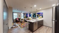 Located at 419 N Herbert Ave in Tucson, AZ, this single-floor residential unit offers a contemporary, energetic living environment with bold design choices and functional layouts. The open-concept kitchen and living area form the heart of the space, where light wood-style flooring flows seamlessly throughout. The kitchen is equipped with stainless steel appliances—including a full-size refrigerator, range, microwave, and dishwasher—complemented by dark wood cabinetry, a tile backsplash, and a spacious island with quartz countertops and pendant lighting overhead. The living area is bright and welcoming, with large windows allowing generous natural light, ceiling fans, and room for comfortable seating arrangements. Two bedrooms offer carpeted floors, ceiling fans, natural light from windows, and dedicated desk spaces ideal for studying or working. One bedroom features a bold accent wall mural, adding a distinctive character to the room. Each bedroom is paired with its own bathroom; one bathroom includes a walk-in shower and an adjacent walk-in closet with built-in shelving, while the other features a vanity with quartz countertops and dark cabinetry. Overall, the unit presents a modern, vibrant aesthetic well-suited for contemporary living in Tucson.