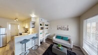 This one-bedroom, one-bathroom unit in Austin, TX offers a thoughtfully designed single-floor layout that maximizes every inch of available space. The open-concept living and kitchen area is defined by a distinctive white built-in shelving unit that serves as both a room divider and a functional display and storage wall, incorporating a compact built-in desk. Hardwood-style flooring runs throughout the main living areas, adding warmth and visual continuity.

The kitchen features white cabinetry, a stainless steel electric range, a stainless steel sink, light countertops, and a breakfast bar with seating for two, making it practical for everyday cooking and casual dining. The living area benefits from large windows that allow generous natural light and includes ample space for a sofa and coffee table arrangement.

The bedroom is a well-proportioned, private retreat with a ceiling fan, a window with exterior views, and the same hardwood-style flooring found throughout. The bathroom includes a full tub and shower combination finished with classic white subway tile, providing a clean and timeless aesthetic. Overall, the unit presents a functional and cohesive design suited to efficient urban living.