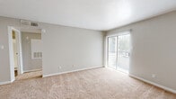 This 1-bedroom, 1-bathroom unit is thoughtfully laid out across a single floor, offering an efficient and comfortable living arrangement. The living room is bright and open, featuring neutral-toned carpet, light-colored walls, and a sliding glass door with vertical blinds that provides outdoor access and fills the space with natural light. The kitchen is a well-equipped galley-style space with white cabinetry, dark granite-style countertops, hardwood-style flooring, and black appliances including a range and refrigerator. A notable feature is the in-unit washer and dryer, conveniently located just off the kitchen. The generously sized bedroom offers plush carpeting, a ceiling fan with light fixture, a natural light-admitting window, and direct access to a dedicated closet complete with a hanging rod for organized storage. The bathroom is clean and functional, featuring a full-size soaking tub and shower combination with a white surround and hardwood-style flooring. Throughout the unit, a consistent neutral color palette and clean finishes create a calm and cohesive aesthetic. The practical floor plan connects all rooms efficiently through a central hallway, making the most of the available space.