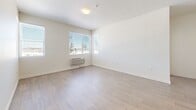 Located at 14475 Montview Blvd in Aurora, CO, this single-floor, 2-bedroom, 1-bathroom unit offers a well-organized layout designed for comfortable everyday living. Wood-look flooring runs consistently throughout the space, lending a clean and cohesive aesthetic from room to room.

The heart of the unit is an open-concept area combining the living room, dining room, and kitchen. The kitchen is equipped with rich dark-toned cabinetry, light marble-style countertops, and a full suite of black appliances including a refrigerator, electric range, built-in microwave, and dishwasher. Track lighting overhead adds functional illumination to the cooking space.

The two bedrooms are bright and airy, each featuring windows that invite natural light and offer views of the surrounding neighborhood. Individual climate control units are present in the bedrooms, ensuring personalized comfort. The primary bedroom includes multiple closet access points, providing ample storage.

The bathroom is clean and functional, featuring a full tub-shower combination with chrome fixtures. A dedicated laundry room houses a stacked front-load washer and dryer unit, adding significant everyday convenience. The layout also includes an entrance, hallway, and additional closet spaces throughout.