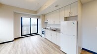 Located at 2346 Weston Rd in Toronto's Weston neighbourhood, this efficiently designed single-floor unit offers a clean, contemporary layout with thoughtful use of space. Light wood laminate flooring runs throughout, complementing the bright white walls and creating a cohesive, modern aesthetic.

The open living area is a standout feature, anchored by large, floor-to-ceiling windows framed in sleek black that flood the space with natural light and offer sweeping elevated views of the surrounding Toronto cityscape and neighbourhoods beyond.

The kitchen is well-appointed with full-height white cabinetry providing generous storage, granite-patterned countertops, a stainless steel sink, a white electric range with overhead ventilation, and a full-size refrigerator — all positioned along a single efficient galley-style wall adjacent to the main living area.

A narrow hallway connects the entry to the main living space, featuring recessed lighting and sliding panel doors that maximize usable floor area. The bathroom is neatly finished with the same light wood flooring, a white vanity topped with granite-style counters, a framed mirror, a glass-enclosed standing shower, and a window providing natural light and ventilation. The overall ambiance is clean, bright, and move-in ready.