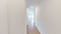 Located at 5901 Triangle Oaks Dr in Raleigh, NC, this thoughtfully designed single-story home offers 1 bedroom and 2 full bathrooms across a generously sized floor plan. Light wood flooring flows seamlessly throughout, complementing the clean white walls and creating a bright, cohesive aesthetic.

The open-concept kitchen and living area serves as the heart of the home. The kitchen features white shaker cabinetry, granite countertops, a large central island with a sink, stainless steel appliances including a refrigerator and microwave, a tile backsplash, and pendant lighting overhead. A private door leads to an outdoor space, while multiple windows flood the area with natural light and exterior views.

The living room is spacious and airy, equipped with a ceiling fan and large windows that frame outdoor greenery. A hallway connects the main living areas to the private bedroom, which includes a ceiling fan, a bright window with outdoor views, and two closets — one of which is a walk-in with wire shelving for ample storage.

The primary bathroom is well-appointed with a dual-sink granite vanity, white cabinetry, and a walk-in glass-enclosed shower. A second full bathroom provides additional convenience. The overall ambiance is clean, modern, and move-in ready.