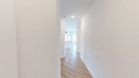 Located at 5901 Triangle Oaks Dr in Raleigh, NC, this thoughtfully designed single-story home offers 1 bedroom and 2 full bathrooms across a generously sized floor plan. Light wood flooring flows seamlessly throughout, complementing the clean white walls and creating a bright, cohesive aesthetic.

The open-concept kitchen and living area serves as the heart of the home. The kitchen features white shaker cabinetry, granite countertops, a large central island with a sink, stainless steel appliances including a refrigerator and microwave, a tile backsplash, and pendant lighting overhead. A private door leads to an outdoor space, while multiple windows flood the area with natural light and exterior views.

The living room is spacious and airy, equipped with a ceiling fan and large windows that frame outdoor greenery. A hallway connects the main living areas to the private bedroom, which includes a ceiling fan, a bright window with outdoor views, and two closets — one of which is a walk-in with wire shelving for ample storage.

The primary bathroom is well-appointed with a dual-sink granite vanity, white cabinetry, and a walk-in glass-enclosed shower. A second full bathroom provides additional convenience. The overall ambiance is clean, modern, and move-in ready.
