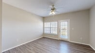 Located at 3500 Quail Creek Drive in Denton, TX, this single-story home offers six bedrooms, two full bathrooms, and a practical, well-organized layout. The interior features a neutral color palette with warm gray tones throughout, creating a clean and cohesive aesthetic. Wood-look luxury vinyl plank flooring runs through the main living areas, kitchen, hallway, and bathrooms, while plush carpet provides comfort in the bedrooms.

The combined kitchen and living room serves as the heart of the home. The kitchen is outfitted with white cabinetry, light countertops, and a full suite of white appliances including a refrigerator, electric range, microwave, and dishwasher. The living area benefits from natural light through large windows and a glass door, accompanied by a ceiling fan with integrated lighting.

The six bedrooms are generously distributed throughout the floor plan, each featuring carpet flooring, ceiling fans, and ample natural light from windows with exterior views. The primary bedroom offers a comfortable footprint with its own closet access.

Both bathrooms are finished with wood-look flooring, white cabinetry, and tiled tub/shower combinations. A dedicated laundry room with washer/dryer hookups and overhead shelving adds everyday convenience. Two closets provide additional storage throughout the home.