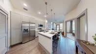 Located in Spring, TX, this well-appointed 2-bedroom, 3-bathroom Casella residence offers a thoughtfully designed single-floor layout that maximizes both comfort and functionality. The open-concept living area seamlessly connects the kitchen and living room, creating an inviting, airy atmosphere. Wood-style flooring flows throughout the main living spaces, complemented by neutral tones and clean lines.

The kitchen is a standout feature, boasting soft gray shaker cabinetry, crisp white quartz countertops, a subway tile backsplash, stainless steel appliances, and a peninsula with pendant lighting and an undermount sink — ideal for casual dining or entertaining. The living room is bright and welcoming, with large windows dressed in blinds and draping curtains that allow ample natural light and outdoor views.

Both bedrooms offer a peaceful retreat with plush carpeting, generous windows, and well-sized closets featuring built-in shelving and hanging rods. The primary bedroom connects to a private bathroom equipped with large-format tile, a glass-enclosed shower, and a vanity with ample storage. A second full bathroom includes a soaking tub and similarly refined finishes. The space is completed by two dedicated closets, providing practical everyday storage throughout.