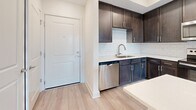Located at 9650 52nd Ave E in Palmetto, Florida, this single-floor, 2-bedroom, 1-bathroom residence offers a thoughtfully designed layout with a clean, modern aesthetic throughout. Light wood-style flooring runs continuously across the space, creating a cohesive and bright atmosphere from room to room.

The kitchen is a standout feature, outfitted with rich, dark-stained cabinetry, white quartz countertops, and a classic subway tile backsplash. A full suite of stainless steel Whirlpool appliances — including a refrigerator, range, over-the-range microwave, and dishwasher — provides functionality and a polished look.

A well-lit hallway connects the living areas to the two bedrooms. The primary bedroom is generously sized and includes ample wall space for flexible furniture arrangements. The second bedroom features a window with natural light and views of outdoor greenery, lending the room an open, airy feel.

The bathroom is finished with a dark wood vanity, white quartz countertop with an undermount sink, a large mirror, and a glass-enclosed shower, offering a clean and contemporary design.

Neutral wall tones, recessed lighting, and white panel doors are consistent throughout, contributing to a fresh, move-in-ready presentation. The overall layout is efficient and functional, making excellent use of the available floor space.