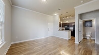 Located at 5525 Mansions Bluffs in San Antonio, TX, this two-bedroom, one-bathroom home offers a well-designed single-floor layout that maximizes every inch of its compact footprint. Throughout the home, warm wood-look flooring and crisp white crown molding create a clean, cohesive aesthetic.

The open-concept living area flows seamlessly into the kitchen, which features rich dark cabinetry with panel detailing, granite-style countertops, a peninsula with a stainless steel sink, pendant lighting, and a full suite of black appliances including a range, microwave, and refrigerator. Track lighting above the peninsula adds both function and style.

The spacious primary bedroom benefits from soaring ceilings that lend an airy feel, while the second bedroom features a large window that fills the room with natural light. A dedicated walk-in closet with built-in shelving and dual hanging rods provides excellent storage.

The bathroom is finished with full floor-to-ceiling tile surrounds in the tub/shower combo, a dark wood vanity with a granite-style countertop, and wood-look flooring. A dedicated in-unit laundry room accommodates a full-size washer and dryer. The home also includes a private patio, completing this practical and comfortable residence.