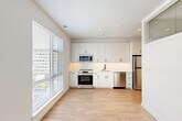 Located at 6400 America Blvd in Hyattsville, MD, this well-designed one-bedroom, one-bathroom unit offers a clean, modern aesthetic throughout. Light wood-style flooring runs continuously across the entire space, complementing the crisp white walls and recessed lighting that give the unit a bright, airy feel.

The entrance leads down a welcoming hallway lined with multiple closets, providing excellent storage capacity. The open-plan kitchen and living area serves as the heart of the unit. The kitchen is outfitted with sleek white cabinetry extending to the ceiling, a herringbone-patterned tile backsplash, stainless steel appliances including a range, over-the-range microwave, dishwasher, and refrigerator, along with a single-basin sink. Large windows flood both the kitchen and living area with natural light, creating an inviting and functional everyday space.

The bedroom is a quiet, private retreat featuring clean white walls, light flooring, and a dedicated closet. The bathroom continues the modern, minimalist design language seen throughout the unit.

With four closets total, the unit offers thoughtful storage solutions. The overall design is cohesive and contemporary, making efficient use of the available space while maintaining a comfortable and functional living environment.