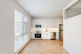 Located at 6400 America Blvd in Hyattsville, MD, this well-designed one-bedroom, one-bathroom unit offers a clean, modern aesthetic throughout. Light wood-style flooring runs continuously across the entire space, complementing the crisp white walls and recessed lighting that give the unit a bright, airy feel.

The entrance leads down a welcoming hallway lined with multiple closets, providing excellent storage capacity. The open-plan kitchen and living area serves as the heart of the unit. The kitchen is outfitted with sleek white cabinetry extending to the ceiling, a herringbone-patterned tile backsplash, stainless steel appliances including a range, over-the-range microwave, dishwasher, and refrigerator, along with a single-basin sink. Large windows flood both the kitchen and living area with natural light, creating an inviting and functional everyday space.

The bedroom is a quiet, private retreat featuring clean white walls, light flooring, and a dedicated closet. The bathroom continues the modern, minimalist design language seen throughout the unit.

With four closets total, the unit offers thoughtful storage solutions. The overall design is cohesive and contemporary, making efficient use of the available space while maintaining a comfortable and functional living environment.