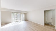 This single-floor residence is designed with a clean, neutral aesthetic throughout. The main living area is bathed in natural light, courtesy of large sliding glass doors fitted with vertical blinds that open to an outdoor space. Light hardwood-style flooring extends across the living and adjoining areas, contributing to a cohesive, airy atmosphere.

The galley-style kitchen is well-appointed with white shaker cabinetry, marble-patterned countertops, a gold-toned faucet, and stainless steel appliances including a refrigerator, oven range, and dishwasher. A ceiling fan overhead adds practicality to the space.

The bedrooms feature neutral carpet flooring and receive natural light through windows dressed with vertical blinds. Generous closet space is provided via louvered bi-fold doors. The layout connects the bedrooms to the main living area through a transitional hallway space.

The bathroom maintains the unit's clean design language, featuring white cabinetry, a single vanity, and light wood-look tile flooring. Grab bars are installed for added accessibility. Throughout, the consistently neutral palette and bright interiors create a welcoming, move-in-ready environment.
