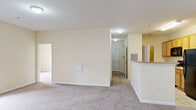 Located at 327 Guinevere in Wilmington, NC, this single-floor unit offers a functional and well-organized layout designed for comfortable everyday living. The open-concept kitchen is a central highlight, featuring warm oak cabinetry with ample storage, light countertops, a full suite of black appliances including a refrigerator, electric range, and over-the-range microwave, and easy-care tile flooring. A wraparound breakfast bar separates the kitchen from the adjacent living area, creating a natural flow between spaces. The living room is generously proportioned, finished with soft wall-to-wall carpeting and neutral cream-toned walls that lend a bright, welcoming atmosphere. French doors open directly onto a private wood-deck balcony, offering pleasant outdoor views of mature trees and the surrounding community. The bedrooms are comfortably sized with plush carpeting, ample wall space, and good natural light. The bathrooms are cleanly finished with a tub/shower combination, a vanity with an integrated sink, a large mirror, and tile flooring. A utility panel is conveniently accessible within the unit. Throughout, the space maintains a clean, move-in-ready aesthetic with consistent neutral finishes, providing a versatile canvas for personalization.