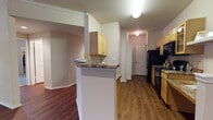 This single-floor residence offers a thoughtfully designed layout that balances functionality and comfort throughout. The open-concept living and dining area is anchored by rich, dark hardwood-style flooring, crown molding, and a ceiling fan, with natural light streaming in through multiple windows and a set of glass doors that open to the outdoors. The kitchen is positioned adjacent to the living space and features light maple cabinetry, granite-style countertops, a tile backsplash, and black appliances including a refrigerator, range, dishwasher, and microwave. A half-wall breakfast bar with a decorative shelf creates a seamless visual connection between the kitchen and the main living area. A hallway leads to the private quarters, where the bedrooms are finished with plush wall-to-wall carpeting, neutral-toned walls, and ample closet space. The bathrooms are well-appointed, each showcasing hardwood-style flooring, light maple vanity cabinetry, granite countertops, large mirrors with bright vanity lighting, and a tub-shower combination. Throughout the residence, clean white trim, panel-style doors, and a consistent warm neutral color palette contribute to a cohesive and inviting atmosphere.