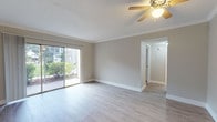 Located at 120 47th Ave N in Saint Petersburg, Florida, this single-floor residence offers a thoughtfully designed layout with a clean, neutral color palette and a blend of hard and soft flooring surfaces. The open living area is finished with light wood-look flooring, crown molding, and a ceiling fan, creating a comfortable and well-ventilated space. Large sliding glass doors flood the room with natural light and provide views of the surrounding greenery, seamlessly connecting the interior to the outdoors. A pass-through window connects the living area to the kitchen, which features crisp white cabinetry, dark granite countertops, a tile backsplash, stainless steel sink, and matching stainless appliances including a dishwasher and range. A charming dining nook with beadboard wainscoting adds a classic touch. The bedrooms are carpeted for comfort, each offering natural light through windows or sliding glass doors, along with generous closet space complete with built-in shelving and hanging rods. The bathroom is well-appointed with a glass-enclosed walk-in shower, a white vanity, and wood-look flooring, maintaining the home's consistent, updated aesthetic throughout.