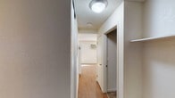 This single-floor unit offers a practical and well-organized layout designed for comfortable everyday living. The interior is connected by a central hallway finished with light hardwood-style flooring and a textured ceiling, providing overhead lighting and access to the key rooms throughout the space.

The galley-style kitchen is efficiently arranged with white cabinetry lining both sides, granite-look countertops, a stainless steel sink, a white refrigerator, and an electric range, offering ample storage and workspace in a compact footprint.

The bathroom features matching granite-look countertops, a single vanity with sink, a window that allows natural light, and a shower/tub combination, complemented by dark hardwood-style flooring.

The bedroom is a comfortably sized room finished with wall-to-wall carpet and a large window fitted with vertical blinds, allowing natural light while maintaining privacy.

The open living area is bright and spacious, featuring warm hardwood-style flooring, a textured ceiling, and a wall-mounted air conditioning unit. A sliding glass door opens to an outdoor area, filling the room with natural light and providing convenient exterior access. The overall interior palette of neutral tones and consistent finishes throughout creates a cohesive and inviting atmosphere.