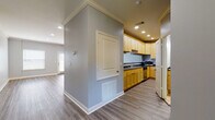 This well-appointed two-story residence offers 2 bedrooms and 2.5 bathrooms, thoughtfully designed for comfortable living across two floors. The open-concept main level features hardwood-style flooring throughout, anchored by a spacious living area with recessed lighting, crown molding, and a ceiling fan. Large windows and glass doors invite abundant natural light and outdoor views, enhancing the airy ambiance of the space.

The kitchen is a functional highlight, showcasing light maple cabinetry, dark countertops, and a full suite of stainless steel appliances including a range, microwave, dishwasher, and refrigerator. A breakfast bar connects the kitchen to the main living area, making it ideal for both cooking and entertaining.

The bedrooms are carpeted for comfort and each features a ceiling fan and natural light from well-placed windows. The primary bathroom includes a double-sink vanity with warm wood cabinetry and dark countertops, while the additional full bathrooms each offer a tub/shower combination with clean, tile flooring. A convenient half bath completes the bathroom count.

The home also includes an attached garage with interior access, providing secure parking and additional storage. Throughout, a consistent cool gray color palette lends a cohesive, modern aesthetic.