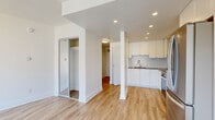 Located at 2190 Bellevue Ave in West Vancouver, BC, this efficiently designed single-floor unit makes excellent use of its compact footprint. The open-concept layout is anchored by a thoughtfully outfitted kitchen featuring crisp white shaker cabinetry, a grey composite countertop, a textured subway tile backsplash, stainless steel appliances including a range and over-the-range microwave, and a functional sink — all set atop light hardwood-style flooring that flows throughout the unit. Recessed pot lighting illuminates the kitchen and adjoining areas, contributing to a clean, modern aesthetic. The living area is a highlight of the space, benefiting from a large floor-to-ceiling window that floods the room with natural light and frames views of the surrounding West Vancouver neighbourhood and North Shore mountains. A full bathroom is finished with neutral porcelain tile flooring, a white subway-tiled tub and shower surround, a quartz-topped vanity, and chrome fixtures, delivering a polished, spa-like feel. Three closets provide generous storage for a unit of this size, including a mirrored sliding-door closet. The unit's clean white walls, consistent flooring, and modern finishes throughout create a bright, cohesive, and move-in-ready living environment.