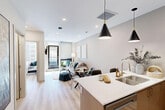 Located in downtown Edmonton, this well-appointed one-bedroom, one-bathroom unit offers a thoughtfully designed open-concept layout finished with light hardwood flooring and a neutral palette throughout. The combined kitchen and living area forms the heart of the unit, where a sleek kitchen features two-toned cabinetry in white and warm taupe, stainless steel appliances including a bottom-freezer refrigerator and gas range, a subway tile backsplash, and a peninsula with bar seating illuminated by pendant lighting. The adjoining living area provides a comfortable and bright setting, enhanced by floor-to-ceiling windows that frame urban city views and allow generous natural light to fill the space. A private balcony extends from the living area, offering direct outdoor access. The bedroom is a well-proportioned retreat featuring a large window with downtown views, recessed wall sconces, and direct access to a dedicated closet. The bathroom is finished with wood-toned tile surround, a full soaker tub with shower, a wood-front vanity with white countertop, and light hardwood-style flooring. Clean lines and modern finishes create a cohesive, contemporary ambiance throughout the entire unit.
