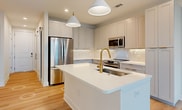 This contemporary apartment showcases a thoughtfully designed interior with a focus on functionality and aesthetics. The open-concept layout creates a seamless flow between living spaces, enhancing the sense of spaciousness. The kitchen is a standout feature, boasting white cabinetry, stainless steel appliances, and a large center island with a stylish gold faucet. Pendant lighting adds a touch of elegance to the cooking area.

Throughout the apartment, light-colored hardwood floors create a warm and inviting atmosphere. The bathroom features a modern vanity with ample counter space and a large mirror. A walk-in closet provides generous storage with built-in shelving and hanging rods.

The bedrooms are well-proportioned, with large windows allowing natural light to flood the spaces. Ceiling fans in some rooms offer additional comfort. The apartment's neutral color palette provides a blank canvas for personalization.

Notable features include recessed lighting, window blinds for privacy, and a blend of contemporary and traditional design elements. The overall ambiance is one of refined comfort, making this apartment an ideal urban retreat.