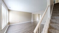 This two-story, 2-bedroom, 2-bathroom home at 5340 Acorn Dr in Indianapolis, IN offers a practical and comfortable layout spread evenly across two floors. The main level features a welcoming entryway with a staircase accented by white railings, leading into an open living and dining area finished with durable wood-style flooring and neutral warm-toned walls. The kitchen is well-appointed with white cabinetry, light stone-patterned countertops, a double stainless steel sink, gas range, dishwasher, and a window that brings in natural light. A full bathroom on the main level features a white vanity with a dark-framed mirror and matching wood-style flooring. The upper level hosts both bedrooms, each carpeted and bathed in natural light from large windows. The primary bedroom is generously sized and features expansive wall-to-wall closet storage with double bi-fold doors. The second bedroom offers outdoor views through a wide multi-pane window. A second full bathroom mirrors the clean, neutral aesthetic found throughout. Additional highlights include a dedicated laundry area, a patio for outdoor enjoyment, a hallway, and an impressive seven closets providing exceptional storage throughout the home.