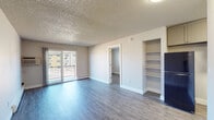 Located at 1060 S Chelton Rd in Colorado Springs, CO, this single-floor unit offers a clean, modernized interior with consistent wood-look flooring throughout. The open living area is a standout feature, bathed in natural light from a large sliding glass door that leads to a private balcony with outdoor views. A textured ceiling adds character to the spacious main living area, which also includes built-in shelving for additional storage and a wall-mounted air conditioning unit for year-round comfort. Baseboard heating runs along the walls, ensuring efficient warmth throughout the space. The kitchen features gray shaker-style cabinetry, granite-look countertops, a black electric range with overhead ventilation, and stainless steel appliances, combining both style and functionality. A dedicated bedroom provides a quiet retreat, complete with closet access and the same wood-look flooring found throughout the unit. The bathroom is neatly appointed with a full tub and shower combination, a vanity with granite-look countertops, and coordinating wood-look flooring. The overall ambiance is bright, clean, and move-in ready, reflecting thoughtful updates that prioritize both comfort and practicality.