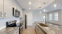 Located at 3220 Champion Ring Rd in Fort Myers, FL, this single-story, 3-bedroom, 2-bathroom home offers a thoughtfully designed open-concept layout. The kitchen is a standout feature, showcasing granite countertops, gray shaker-style cabinetry, a decorative tile backsplash, and a full suite of stainless steel appliances including a range, over-the-range microwave, and refrigerator. A central island with a deep single-basin sink is illuminated by elegant pendant lighting, seamlessly connecting the kitchen to the dining and living areas. Light wood-look flooring flows throughout the home, contributing to a clean, cohesive aesthetic. The bedrooms are bright and well-proportioned, each benefiting from natural light through large windows with blinds and ceiling fans for year-round comfort. The primary bedroom offers generous space with closet access. The bathrooms are finished with granite-topped vanities, gray cabinetry, and a tiled tub-shower combination. A dedicated laundry room houses a full-size side-by-side washer and dryer with overhead shelving. With six closets spread throughout, storage is plentiful. The home's neutral palette and modern finishes create a fresh, move-in-ready atmosphere.