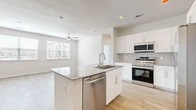 This thoughtfully designed 2-bedroom, 3-bathroom residence offers a bright, open-concept layout with a cohesive modern aesthetic. Light wood-tone flooring flows seamlessly throughout the entire space, creating a warm and airy atmosphere enhanced by neutral wall tones and abundant natural light.

The kitchen serves as a central hub, featuring a large granite-topped island with an undermount sink and integrated dishwasher, crisp white cabinetry, a tile backsplash, and a full suite of stainless steel appliances including a side-by-side refrigerator with ice dispenser, range, microwave, and dishwasher. The kitchen opens directly into the living area, which benefits from a ceiling fan and window views.

Both bedrooms are generously proportioned, each equipped with ceiling fans and access to dedicated closet space. The primary bedroom includes a spacious walk-in closet outfitted with wire shelving systems for organized storage. The bathrooms are finished with marble-look tile surrounds on the tub and shower areas, granite vanity countertops, white cabinetry, and large mirrors. A soaking tub is featured in one of the bathrooms, adding a refined touch.

Overall, the residence presents a clean, contemporary design with consistent finishes that create a cohesive and functional living environment.