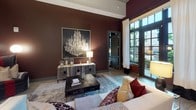 Located in Charleston's desirable 29403 zip code, this single-floor residence at 134 Columbus St combines modern design with sophisticated, curated interiors. The living area makes a striking impression with soaring ceilings, deep burgundy accent walls, and tall grid-pane doors and windows that flood the space with natural light and offer views of lush outdoor surroundings. A tufted sofa, layered rugs, and bold artwork contribute to the room's refined yet warm ambiance.

The kitchen is outfitted with high-gloss gray cabinetry extending to the ceiling, white quartz countertops, a classic subway tile backsplash, and a full suite of stainless steel appliances, including a range, microwave, and refrigerator. Light wood-tone flooring runs throughout, lending continuity and warmth.

The bedroom features cool gray walls, a tufted upholstered headboard, and a large-format art piece above the bed. A generous grid-pane window frames outdoor greenery, offering an abundance of natural light. The bathroom is finished with dual undermount sinks set in a sleek gray vanity, white quartz countertops, large-format dark floor tiles, a wide frameless mirror, and a glass-enclosed walk-in shower with marble-style tile surround.