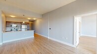 Located at 515 E Market St in the heart of downtown Indianapolis, this modern one-bedroom, two-bathroom unit offers a well-designed open-concept layout finished with light hardwood-style flooring and cool-toned gray walls throughout. The combined kitchen and living area serves as the centerpiece of the home, where a sleek kitchen island with a crisp white quartz countertop and an integrated sink anchors the space. Dark espresso cabinetry, stainless steel appliances — including a refrigerator, range, and microwave — and pendant lighting above the island add a refined, contemporary feel. The living area extends to a private balcony through large sliding glass doors, offering elevated views of the Indianapolis skyline and surrounding cityscape, while flooding the interior with natural light. The generously sized primary bedroom provides ample room for a full furniture arrangement and connects to the corridor leading to both bathrooms. One bathroom features a sliding-glass enclosed walk-in shower with chrome fixtures. A dedicated in-unit laundry room with a full-size washer and dryer adds everyday convenience. A hallway with a closet completes the functional layout of this well-appointed downtown residence.