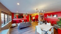 Located at 9710 Zelzah Ave in the Northridge neighborhood of Los Angeles, this single-floor amenity space makes a striking visual statement through its bold red, gray, and accent color palette carried consistently throughout every zone.

The main open-plan lounge area serves as the heart of the space, anchored by hardwood-style flooring, recessed lighting, and a distinctive pendant globe chandelier. A vivid red feature wall bearing a "MUSIC" sign frames a wall-mounted flat-screen TV flanked by bar stools, creating an energetic entertainment hub. Comfortable seating arrangements, including a gray sofa and coordinating accent chairs, invite socializing and relaxation, while a dining table and chairs provide a dedicated area for gathering.

A quieter lounge nook features gray armchairs, music-themed artwork, and warm pendant lighting, offering a more relaxed retreat within the same space. Large windows along one wall bring in natural light and views of the exterior balcony.

The fitness room is equipped with a treadmill, elliptical, and stationary bike set against a dramatic red ceiling and a large black-and-white Los Angeles cityscape mural, creating an energizing workout environment.

A dedicated gaming room, accessible through a frosted glass door, features textured stone-look wall panels, LED triangle light panels, dual monitors, and racing-style gaming chairs, delivering a fully immersive experience for gaming enthusiasts.