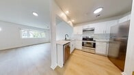 This 730 sq ft, single-floor unit offers 2 bedrooms, 1 bathroom, and a dedicated closet. The open-concept kitchen and living area is anchored by white shaker cabinets, marble-style countertops, a peninsula with an undermount sink, and stainless steel appliances including a range and refrigerator. Recessed lighting and light hardwood flooring run throughout. The living area features a large window and a distinctive octagonal accent window, filling the space with natural light. Both bedrooms are bright and neutral, with the primary bedroom measuring 120 sq ft. The bathroom includes a white vanity, mirror, toilet, and glass-enclosed shower, finished with matte black fixtures for a modern touch.