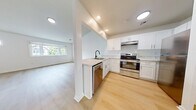 This 730 sq ft, single-floor unit offers 2 bedrooms, 1 bathroom, and a dedicated closet. The open-concept kitchen and living area is anchored by white shaker cabinets, marble-style countertops, a peninsula with an undermount sink, and stainless steel appliances including a range and refrigerator. Recessed lighting and light hardwood flooring run throughout. The living area features a large window and a distinctive octagonal accent window, filling the space with natural light. Both bedrooms are bright and neutral, with the primary bedroom measuring 120 sq ft. The bathroom includes a white vanity, mirror, toilet, and glass-enclosed shower, finished with matte black fixtures for a modern touch.